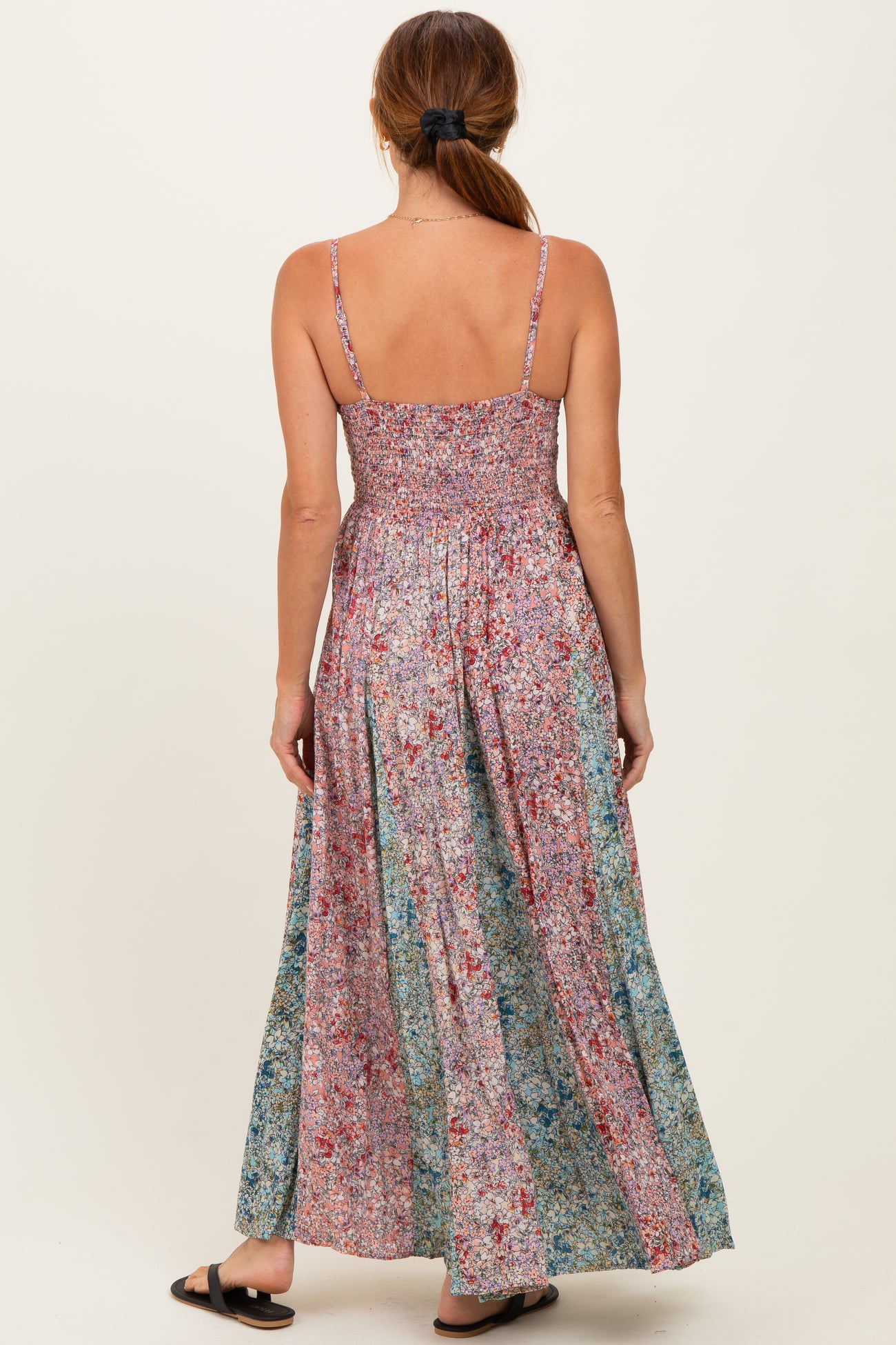 woman wearing a floral maxi dress with a smocked bodice and adjustable straps, viewed from the back