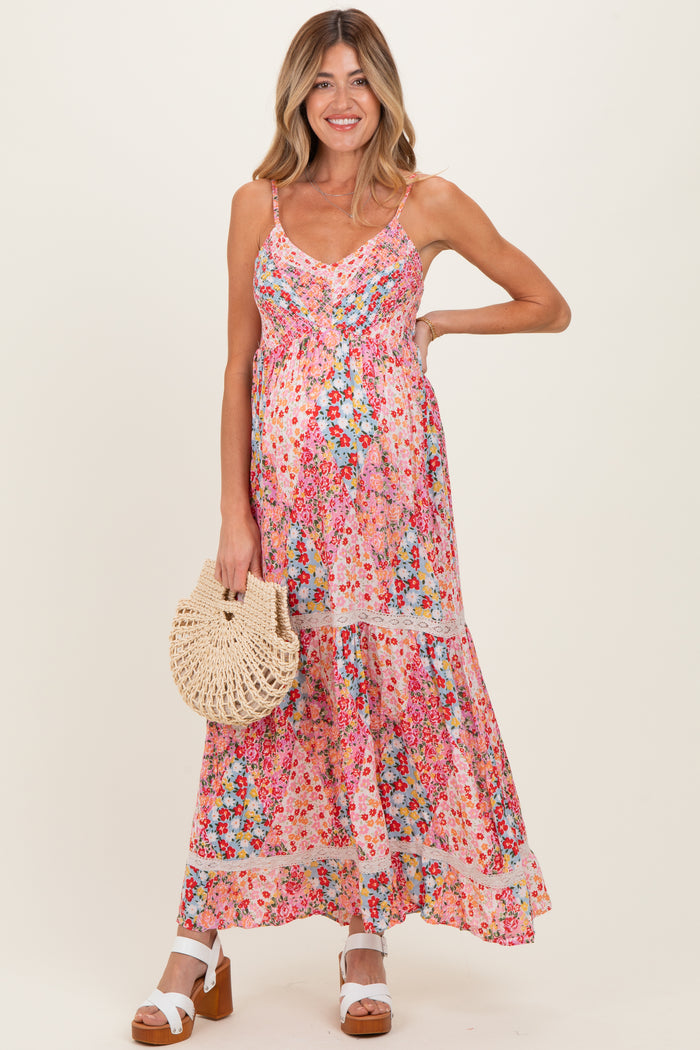 woman wearing a floral maternity maxi dress with adjustable straps and a baby bump, holding a woven bag