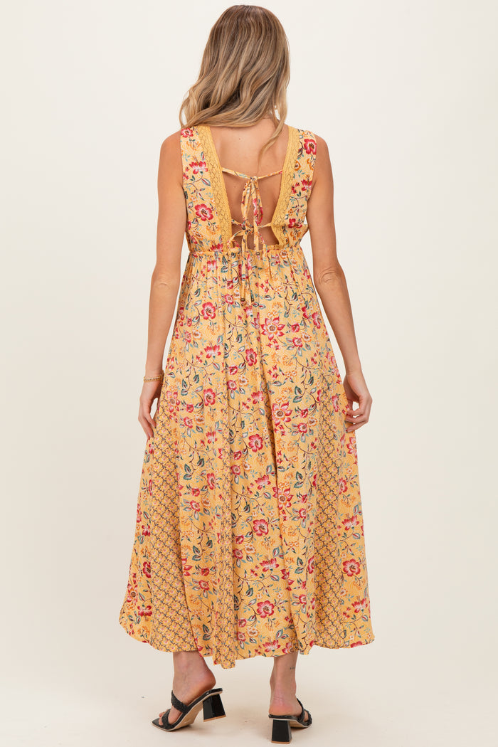 woman wearing a yellow floral maternity maxi dress with a tie back and open back detail, showing style details