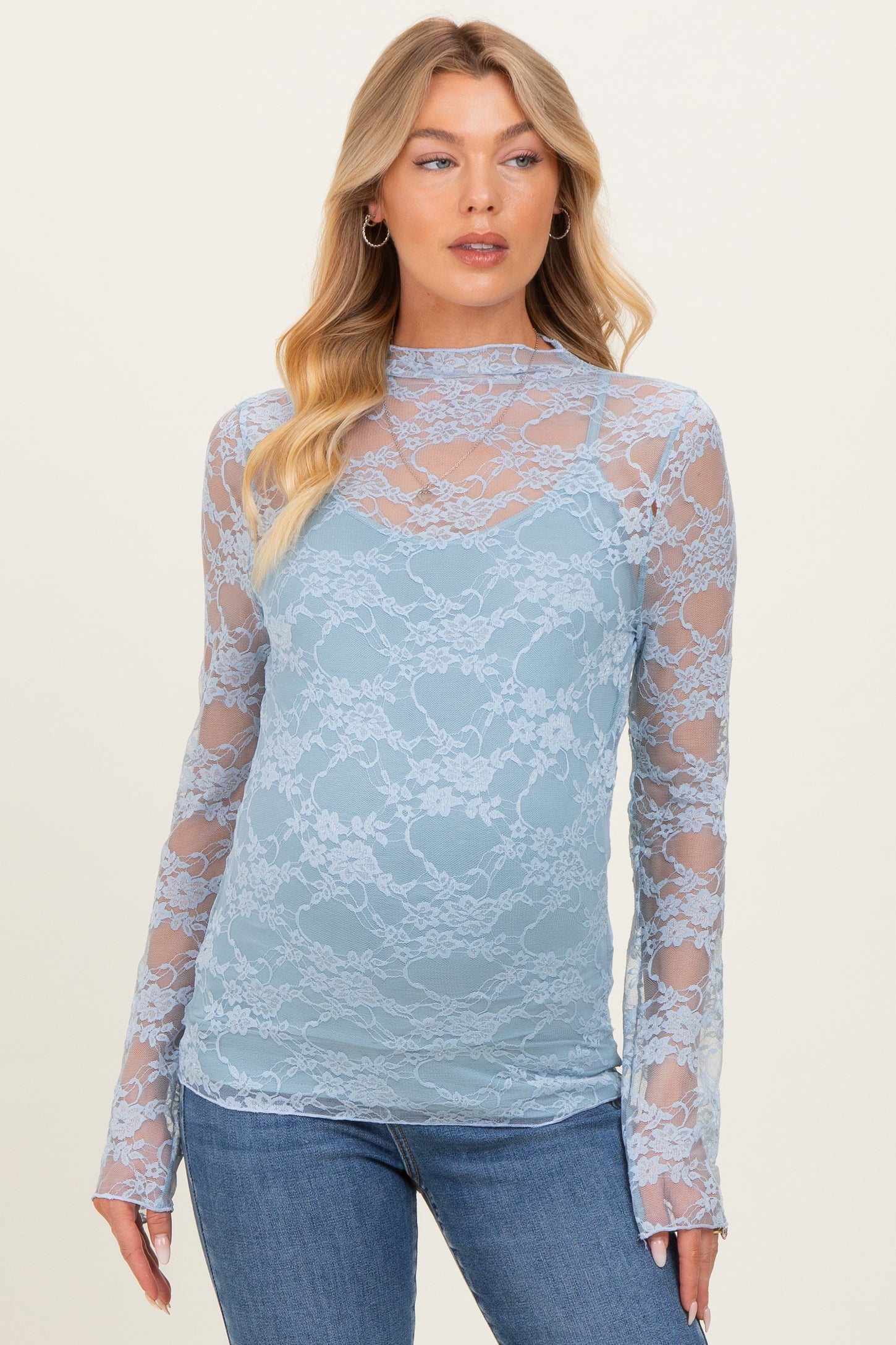 woman wearing a light blue lace maternity top with long sleeves and a scoop neckline, styled over a cami