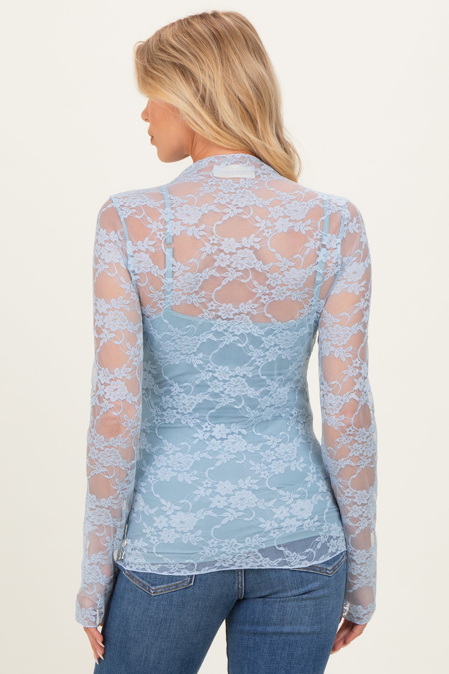 woman wearing a light blue long sleeve lace maternity top, showing a floral pattern from the back