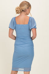 woman wearing a light blue polka dot midi dress with puff sleeves and ruched detailing at the waist