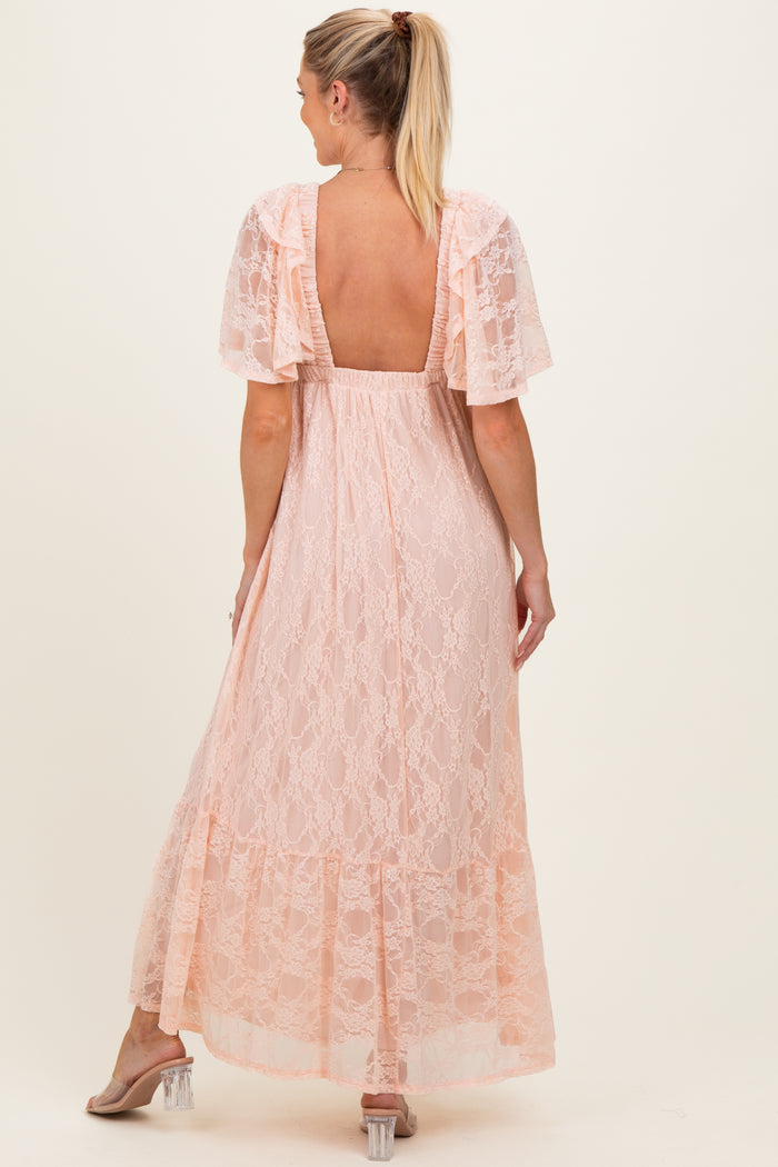 woman wearing a light pink lace maternity maxi dress with short sleeves and a backless design