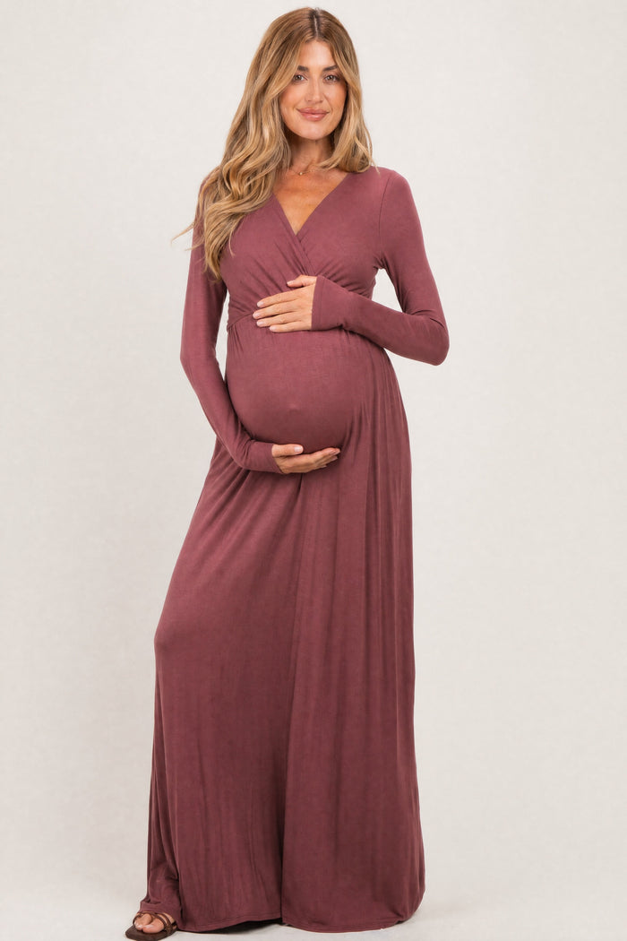 woman wearing a mauve long sleeve maternity dress and holding her baby bump
