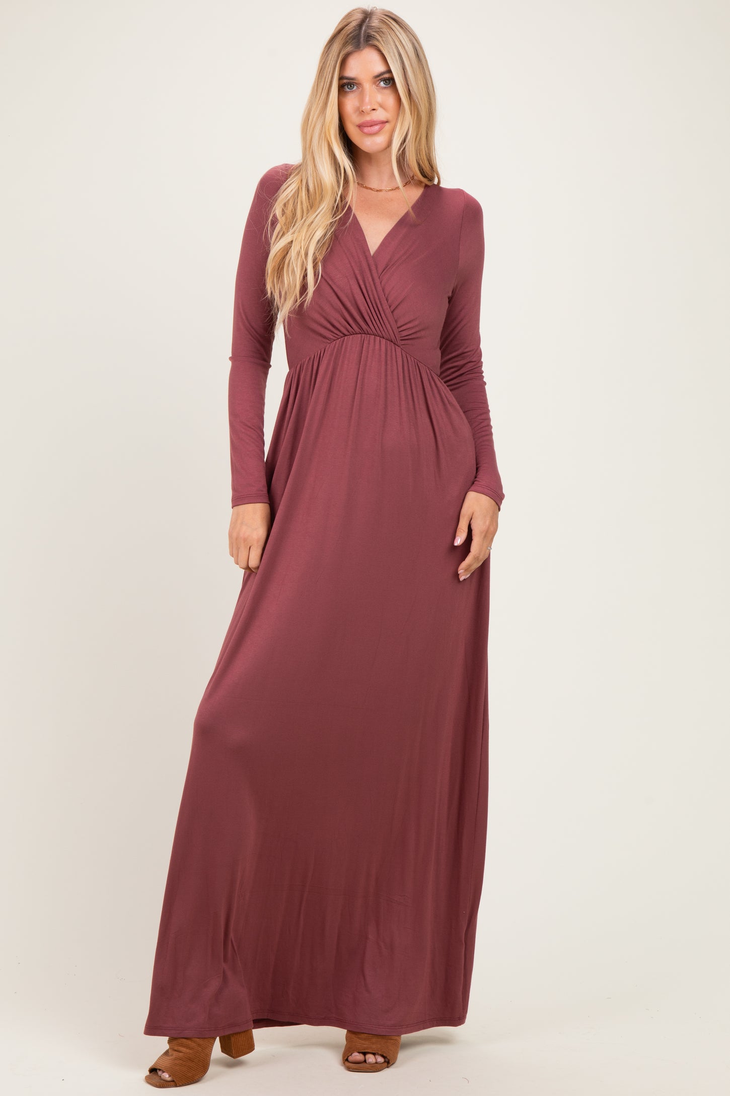 woman wearing a long sleeve burgundy maxi dress with a wrap style and fitted waist