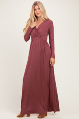 woman wearing a long sleeve maroon wrap maxi dress with a fitted bodice and flowy skirt