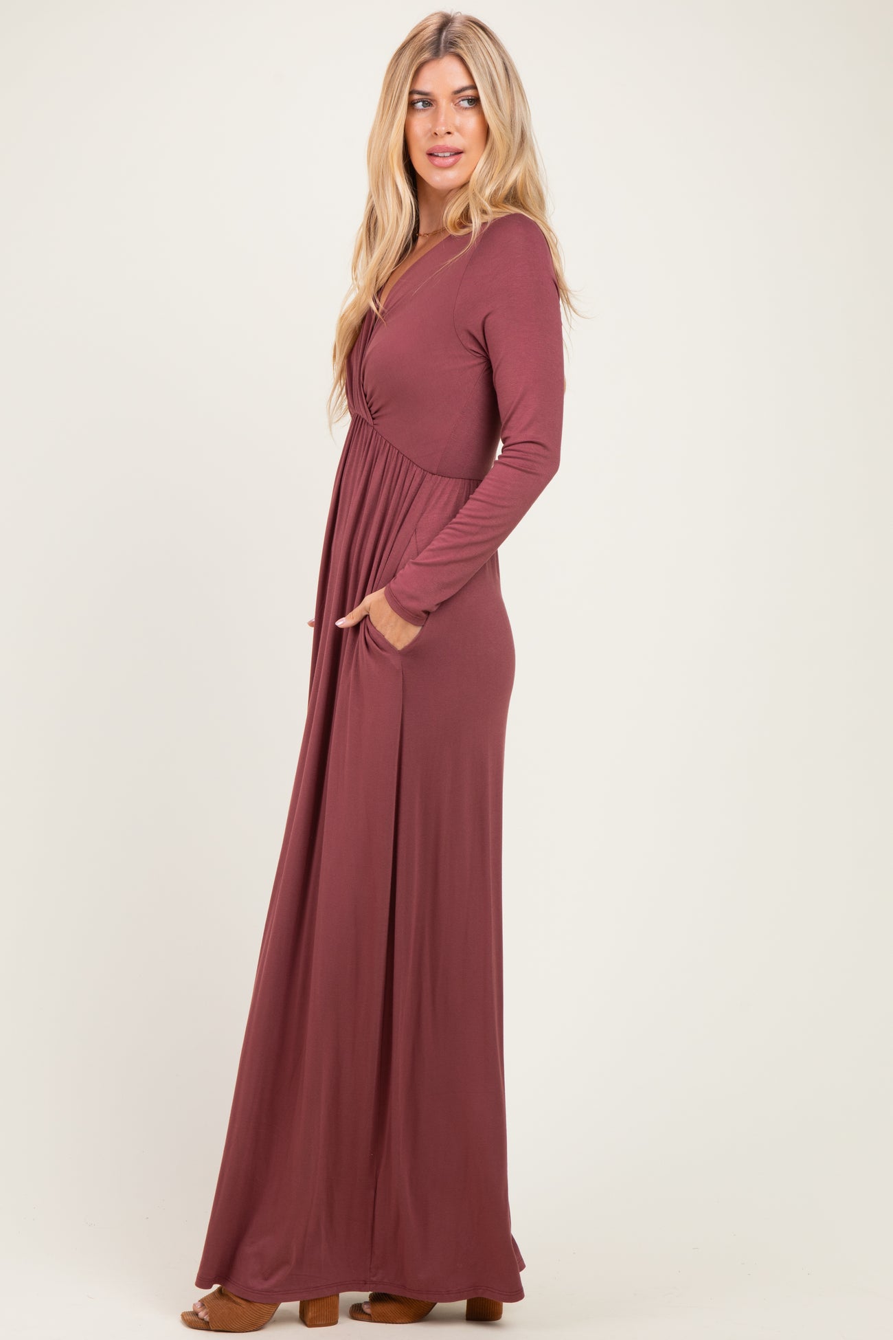 woman wearing a long sleeve burgundy maxi dress with a wrap style and side pockets