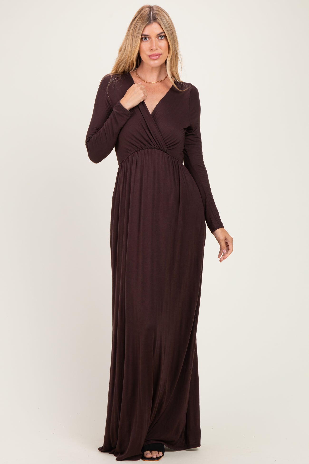 woman wearing a dark brown long sleeve maxi dress with a wrapped bodice and a flowing skirt