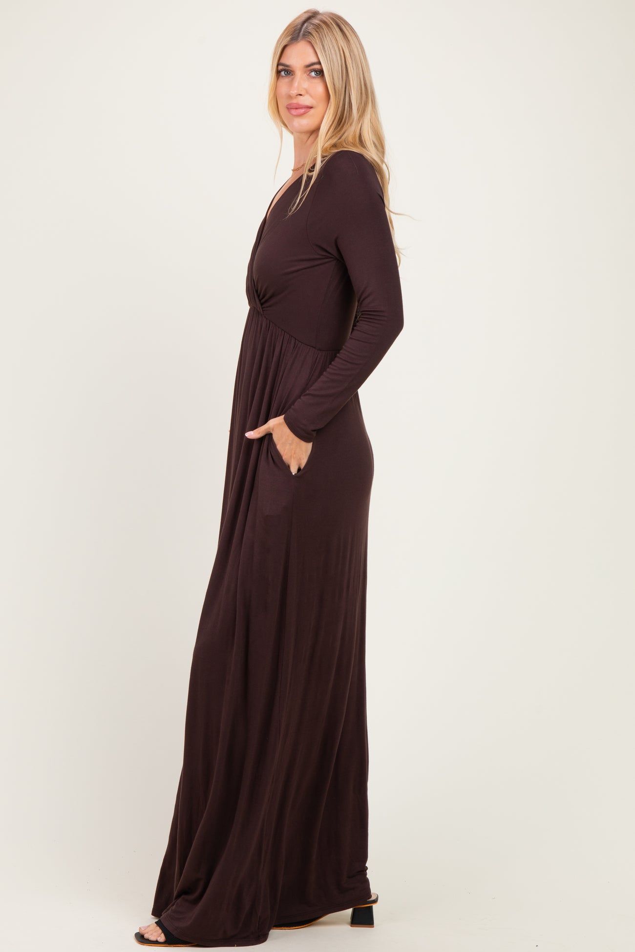 woman wearing a chocolate brown long sleeve maxi dress with a cinched waist and side pockets