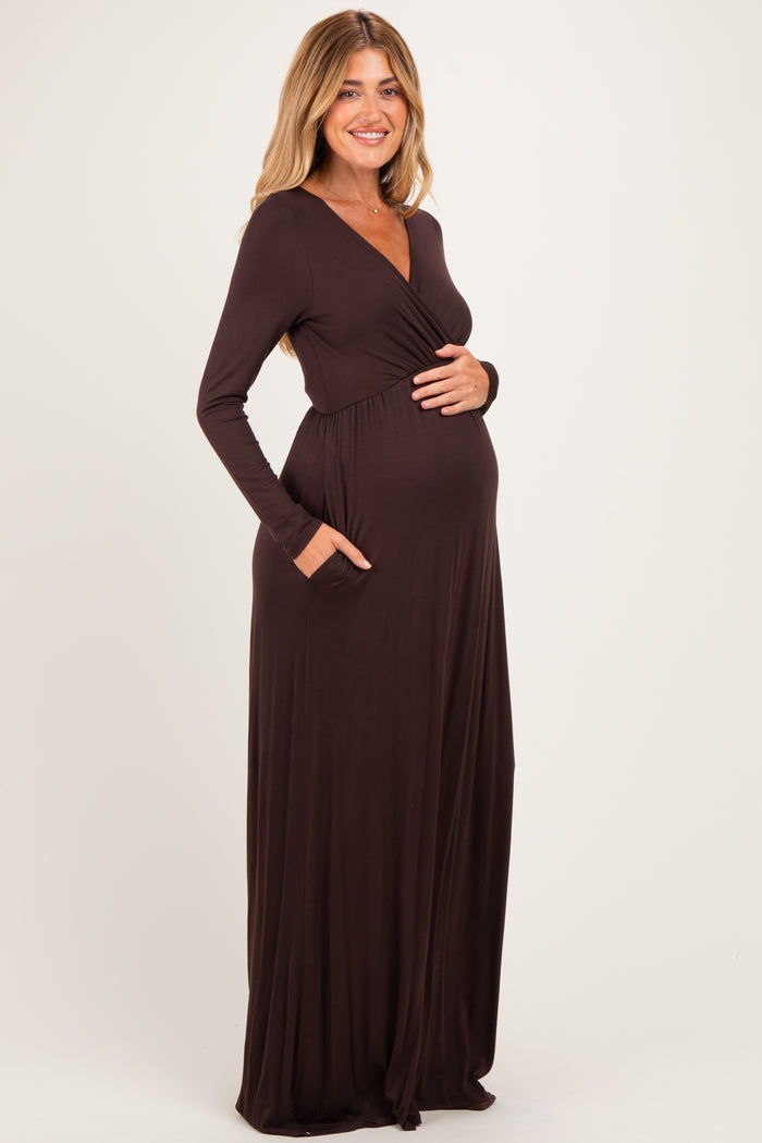 woman wearing a dark brown long sleeve maternity maxi dress with pockets and showing her baby bump
