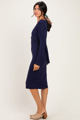 woman wearing a navy blue long sleeve dress with a tie detail at the back and paired with beige heeled mules