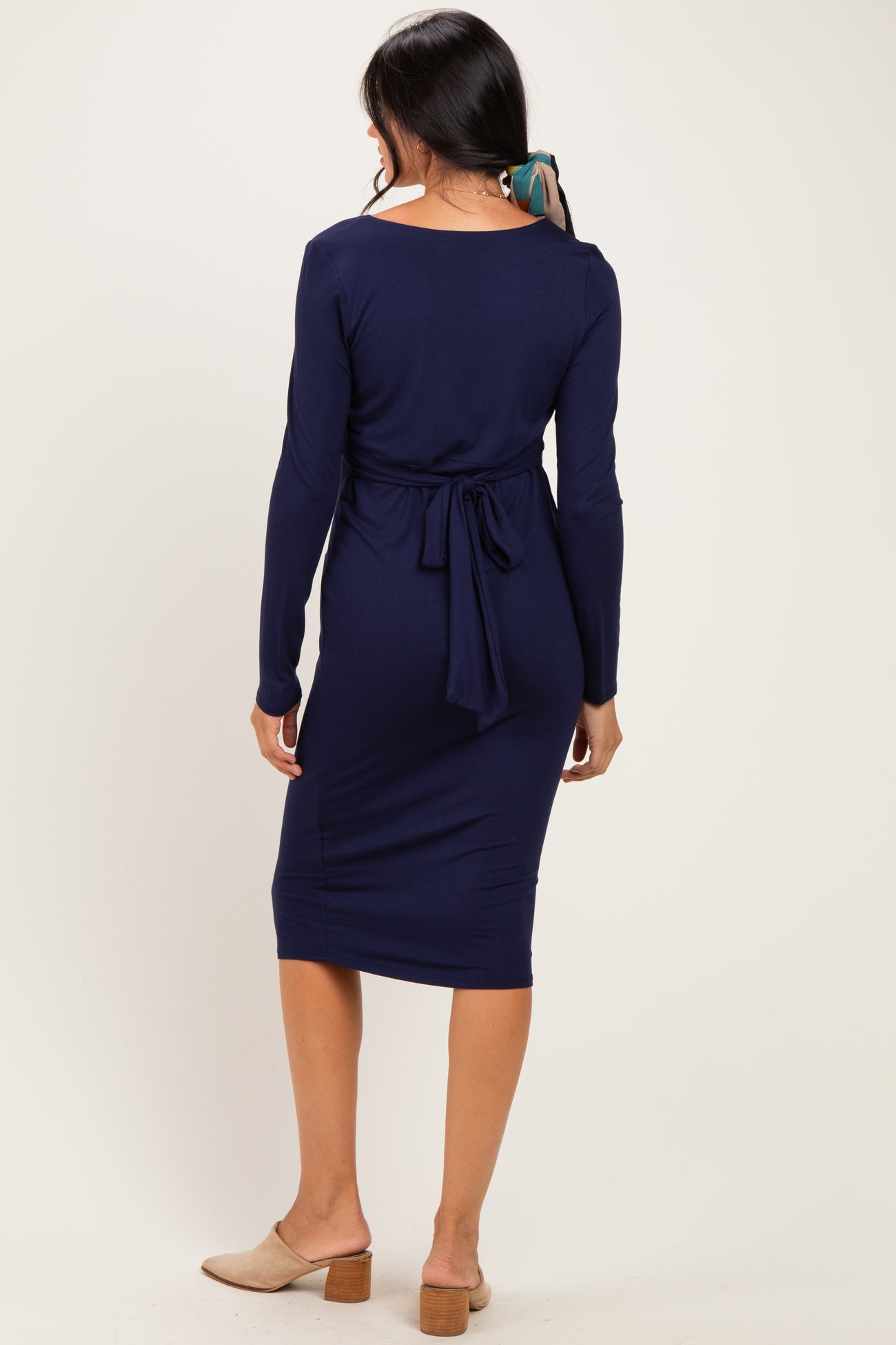 woman wearing a navy long sleeve bodycon dress with a tied waist detail and a midi length