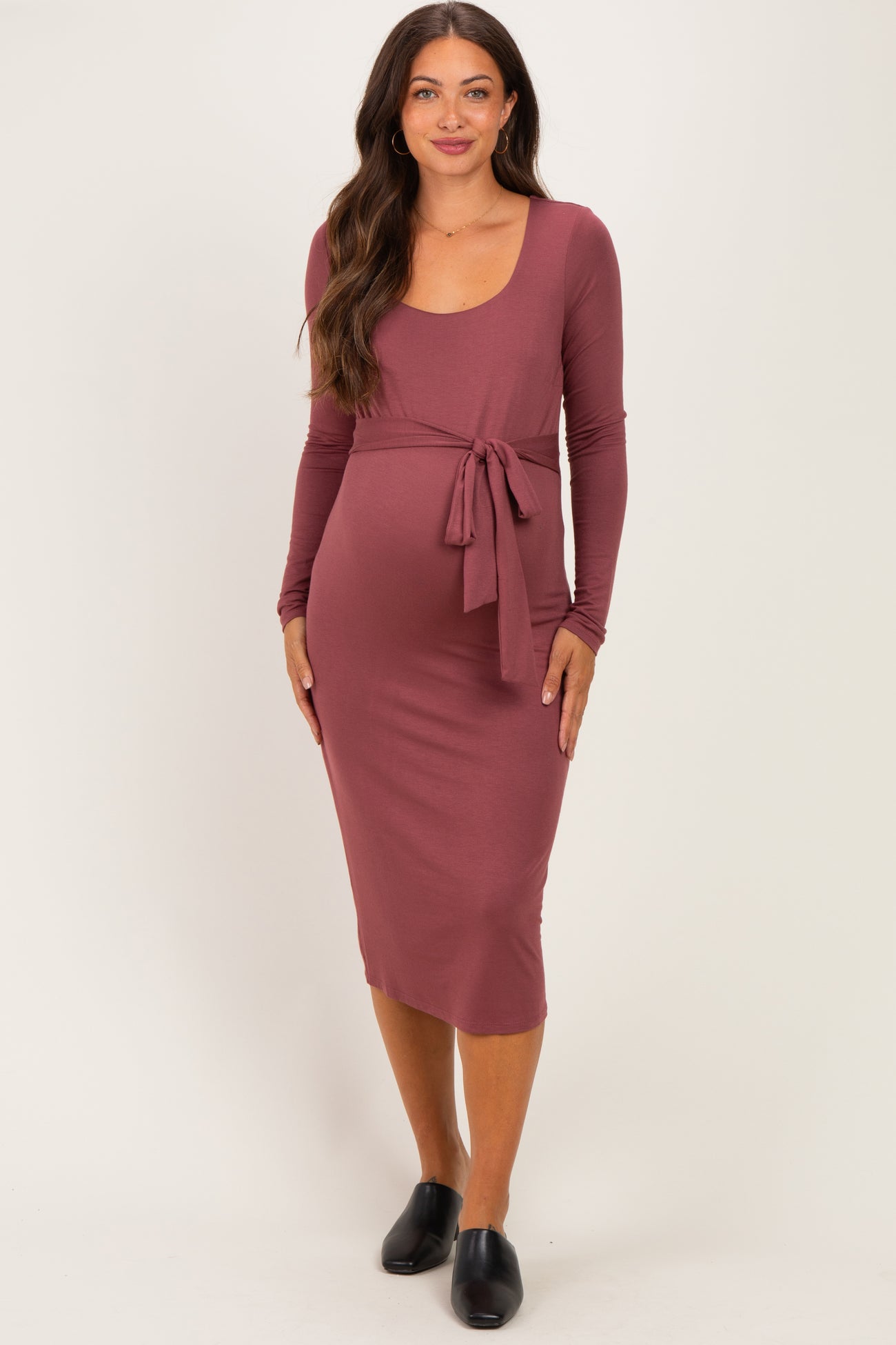 woman wearing a mauve long sleeve maternity dress with a tie at the waist and a visible baby bump