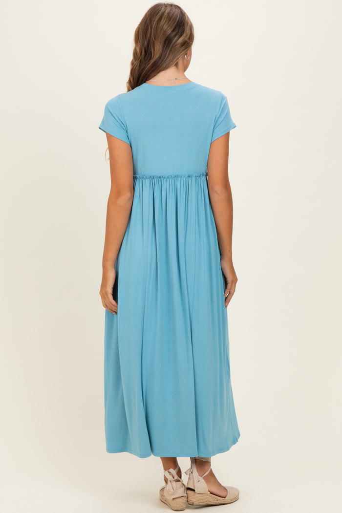 woman wearing a light blue maxi dress with cap sleeves and a gathered waist, viewed from the back