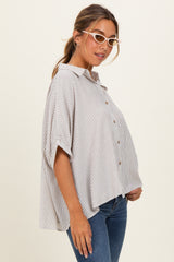 woman wearing a striped oversized button-up shirt with short sleeves and light denim jeans