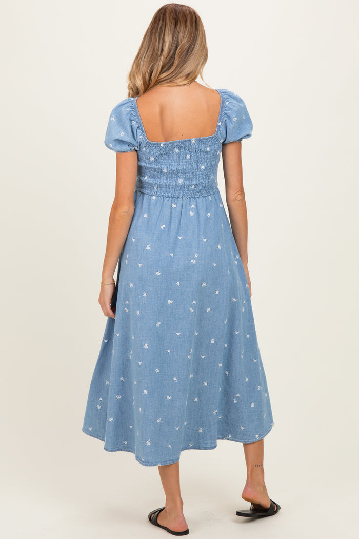 woman wearing a light blue maternity dress with puff sleeves and floral print, showing a baby bump from the back