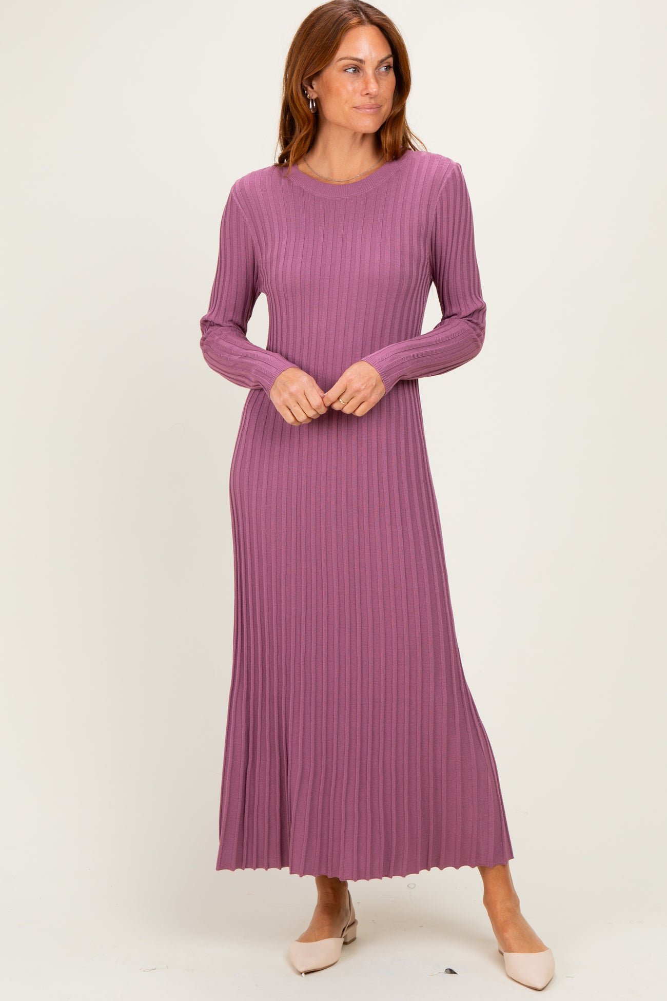 woman wearing a long sleeve ribbed mauve maxi dress with a scalloped hemline and standing confidently