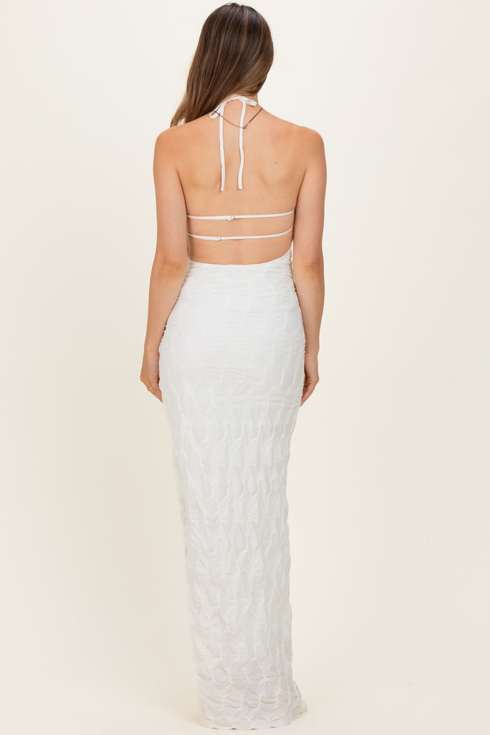 woman wearing a white halter neck maternity dress with a fitted silhouette and strappy back details