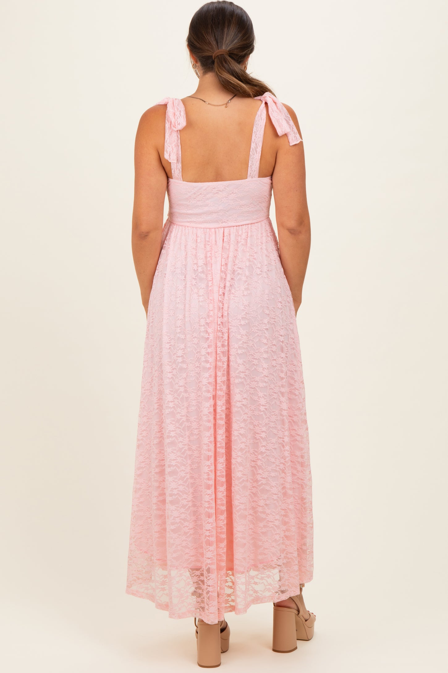 woman wearing a pink maternity maxi dress with tie straps and a flowy skirt, showing a baby bump from the back