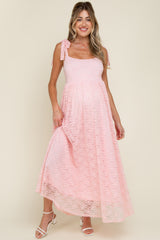 woman wearing a pink lace maternity maxi dress with tie shoulder straps and a visible baby bump