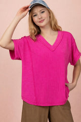 woman wearing a bright pink short sleeve v-neck top with textured fabric and a relaxed fit