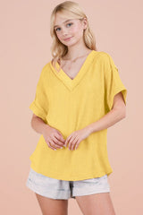 woman wearing a yellow short sleeve v-neck sweater with a relaxed fit and styled with light denim shorts