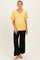 woman wearing a yellow ribbed short sleeve maternity top and black wide-leg pants, showcasing her baby bump