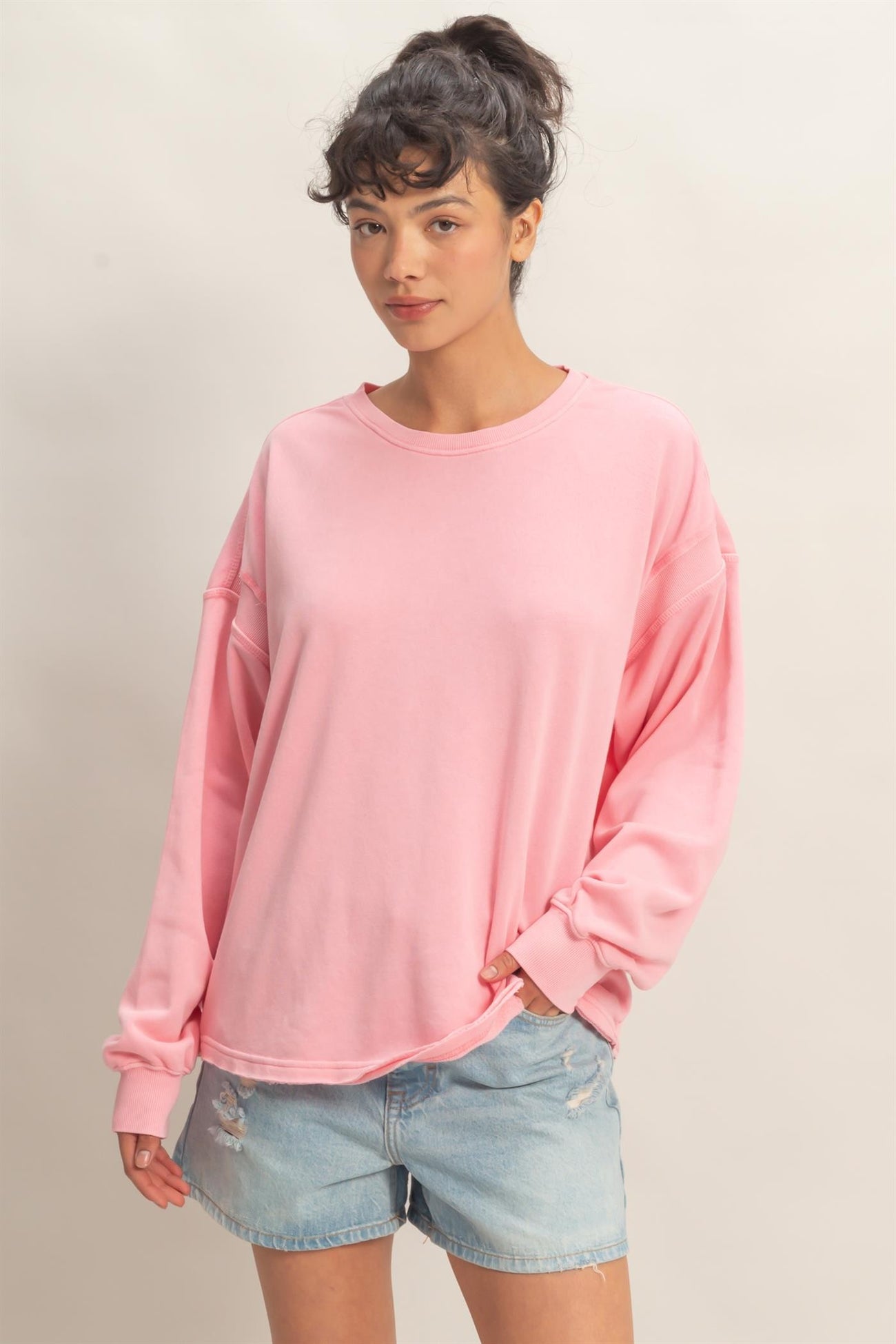 woman wearing a pink oversized long sleeve sweatshirt and denim shorts