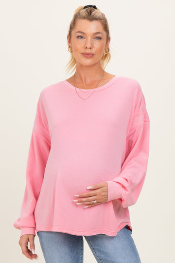 woman wearing a pink long sleeve maternity sweatshirt and holding her baby bump