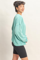 woman wearing a turquoise oversized sweatshirt with an open back and paired with black bike shorts