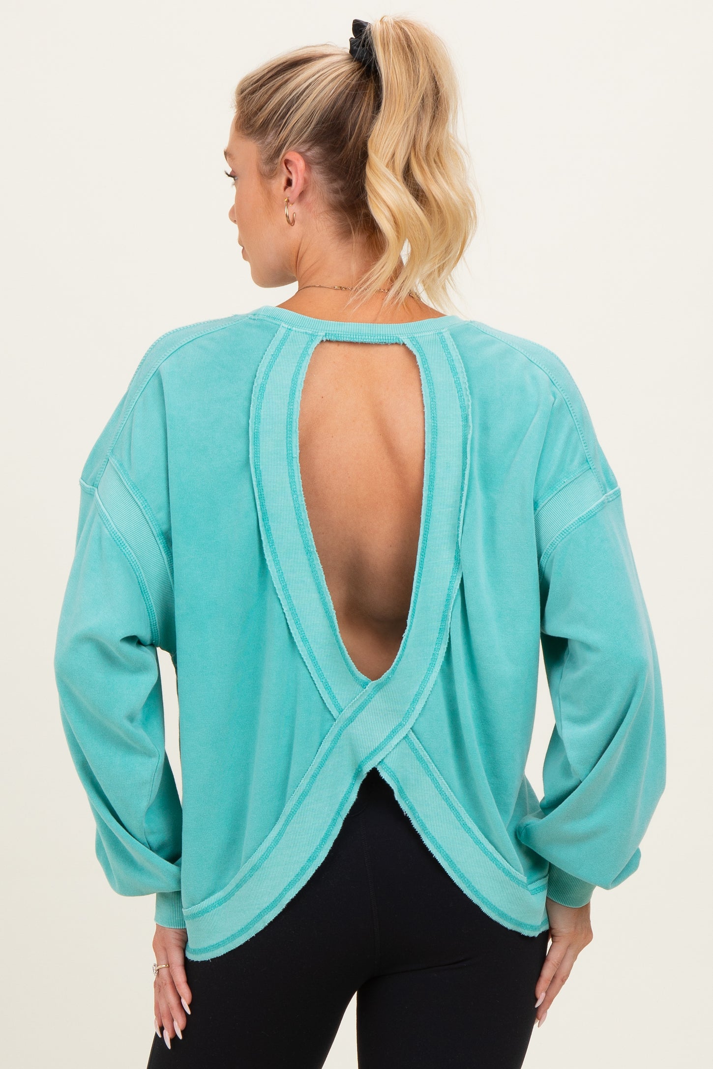 woman wearing a turquoise open back maternity sweatshirt with long sleeves and relaxed fit