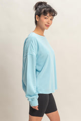 woman wearing a light blue oversized sweatshirt with long sleeves and paired with black bike shorts