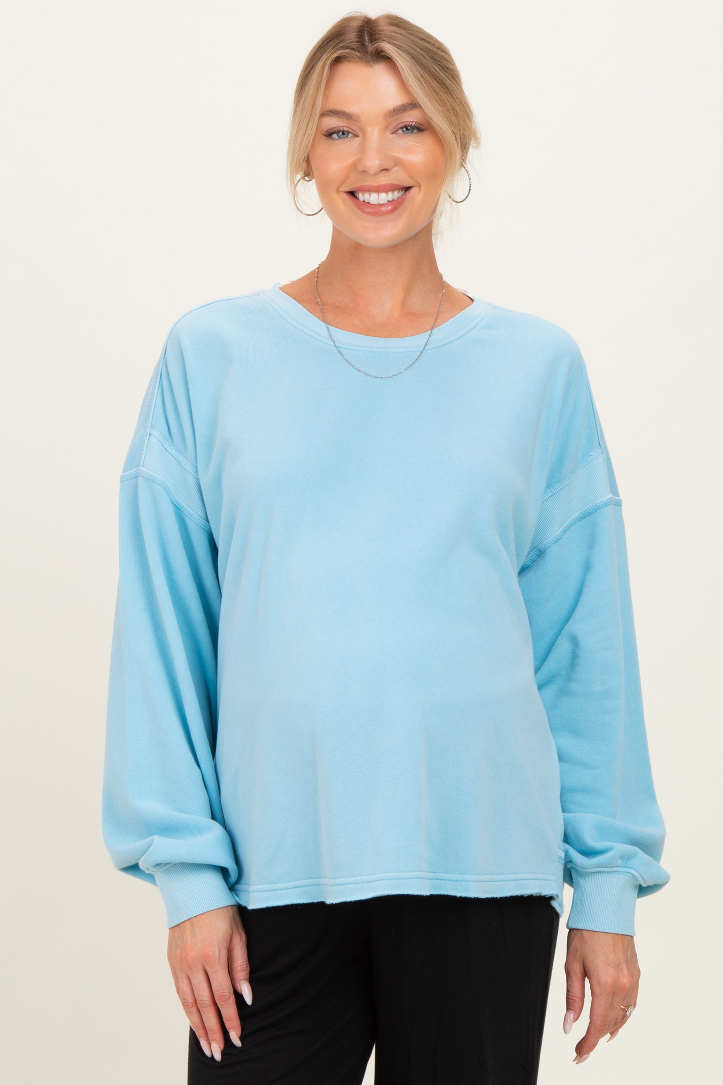 woman wearing a light blue maternity sweatshirt with oversized sleeves and a relaxed fit, baby bump visible