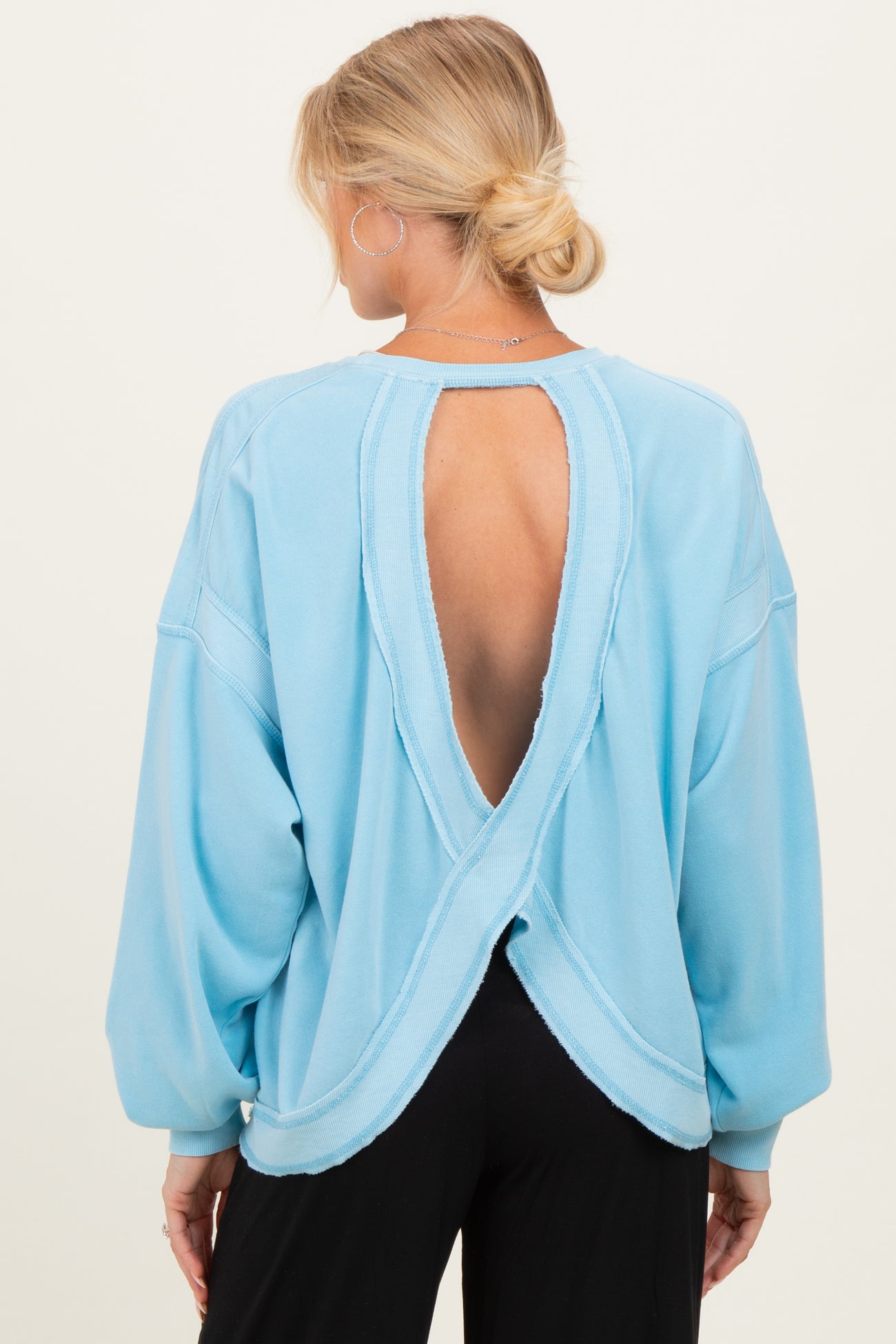 woman wearing a light blue maternity sweatshirt with an open back and long sleeves