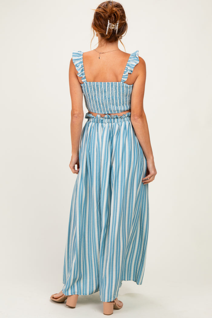 woman wearing a blue and white striped two-piece set with ruffled straps and a flowy maxi skirt
