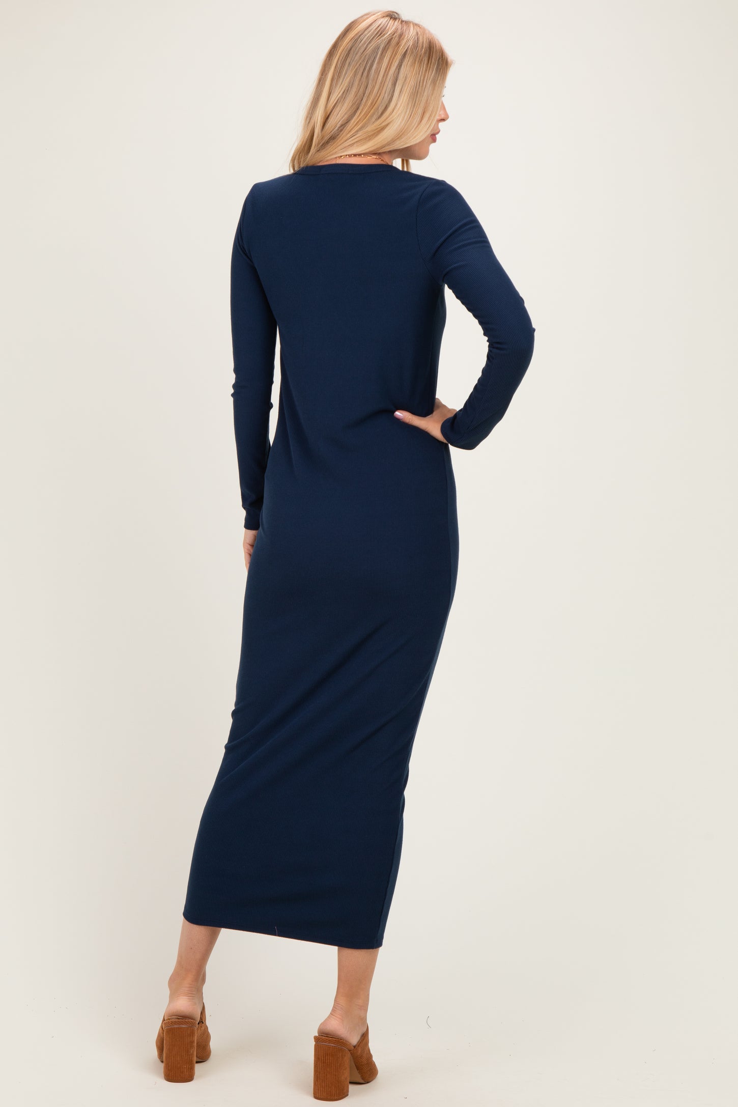 woman wearing a navy blue long sleeve maxi dress, showing the back view and a fitted silhouette