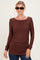 woman wearing a brown long sleeve top with ruching at the sides and sunglasses, standing against a plain background