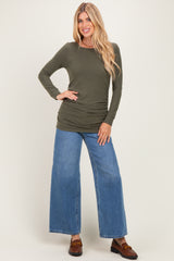 woman wearing an olive green long sleeve top with ruched sides and wide leg blue jeans