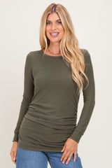 woman wearing an olive green long sleeve top with gathered side detail and casual fit