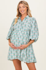woman wearing a patterned green maternity dress with elbow-length sleeves and holding her baby bump