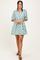 woman wearing a teal patterned short dress with a V-neck and three-quarter sleeves
