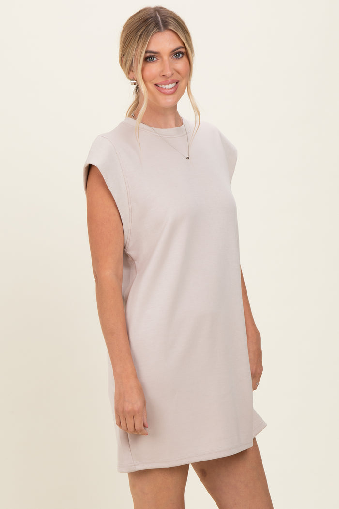 woman wearing a light beige sleeveless dress with a relaxed fit and shoulder detailing