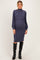 woman wearing a dark blue maternity sweater dress with long puff sleeves and a fitted skirt, showcasing her baby bump