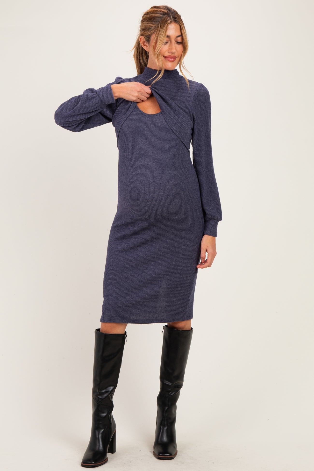 woman wearing a dark blue maternity dress with cut-out detailing and long sleeves, showcasing her baby bump