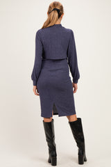 woman wearing a navy blue maternity dress with a fitted silhouette and long sleeves, featuring a back slit