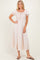 woman wearing a light pink puff sleeve midi dress with a smocked bodice and a tie detail at the neckline