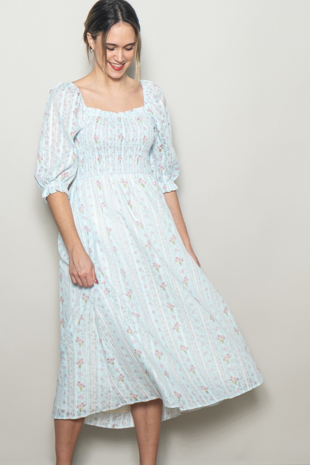 woman wearing a light blue floral midi dress with puff sleeves and a smocked bodice