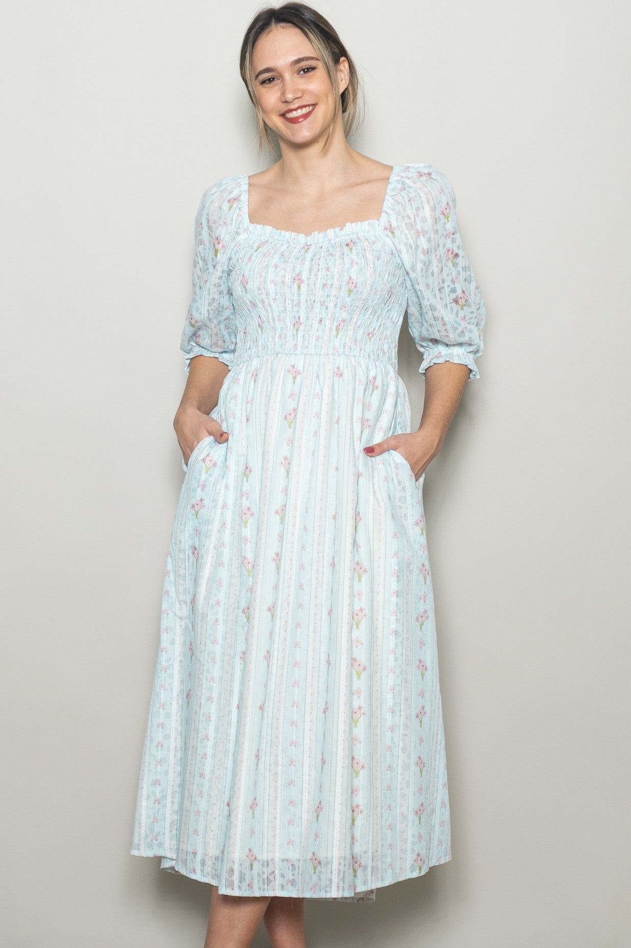 woman wearing a light blue floral midi dress with puff sleeves and pockets