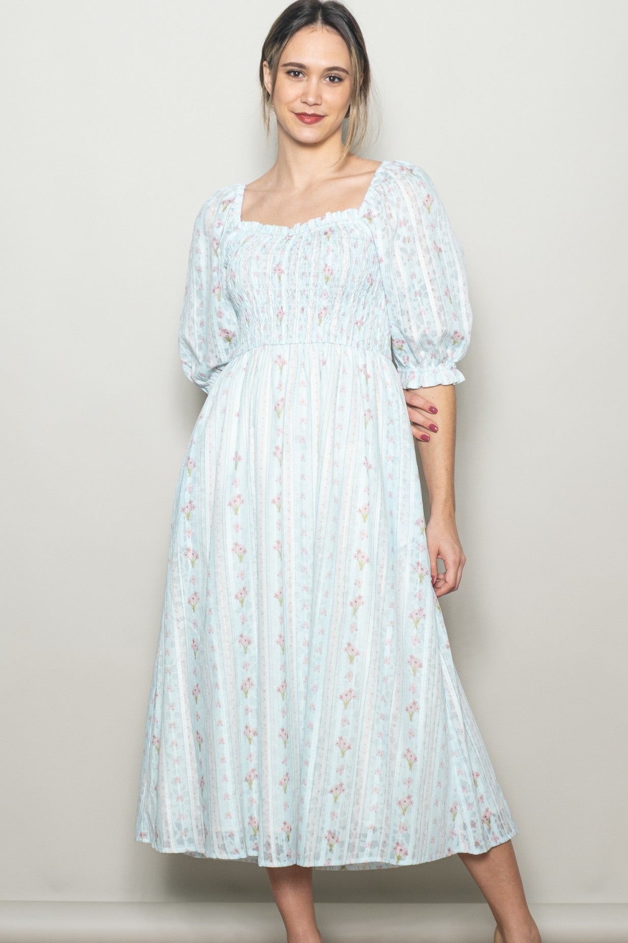 woman wearing a light blue floral midi dress with puff sleeves and a smocked bodice