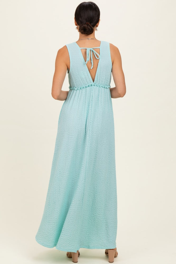 woman wearing a light blue maxi dress with a back tie detail and gathered waist, shown from the back